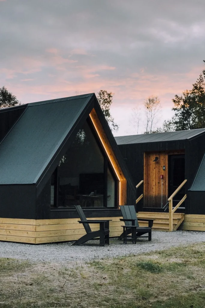 a black house with a triangle roof and chairs outside