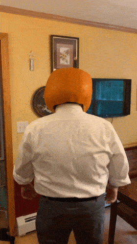 a person wearing a white shirt and white shirt with a large orange object on their head