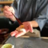 a person holding a brush over a sushi