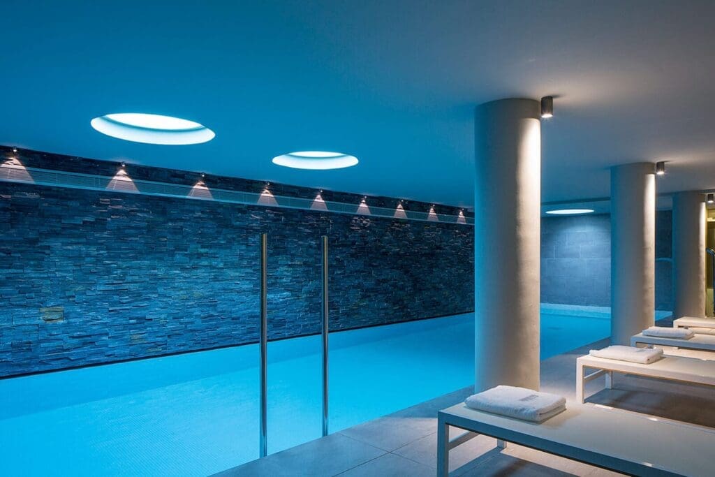 a pool with a stone wall and a white bench