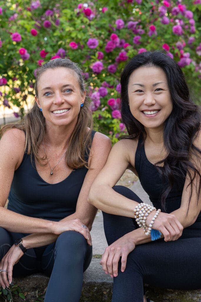 two women sitting on a sidewalk