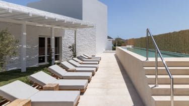 a pool with lounge chairs and a pool in the background