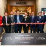 a group of people in suits cutting a red ribbon