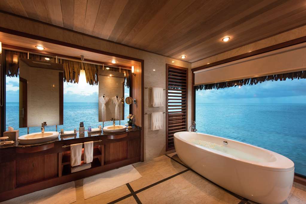 a bathroom with a tub and sinks and a window overlooking the ocean